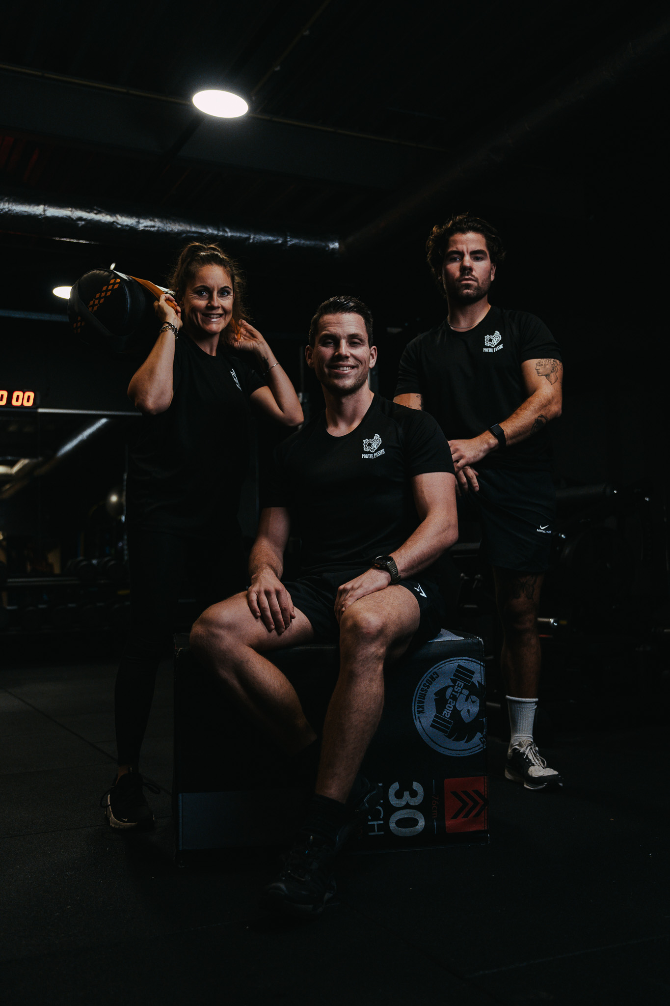 Coaches en deelnemer lachend samen in de gym